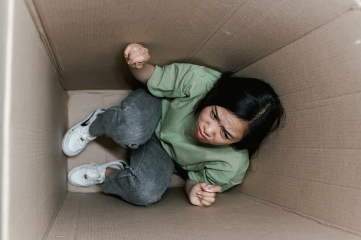 a fearful woman having claustrophobia in a cardboard box stockpack pexels scaled