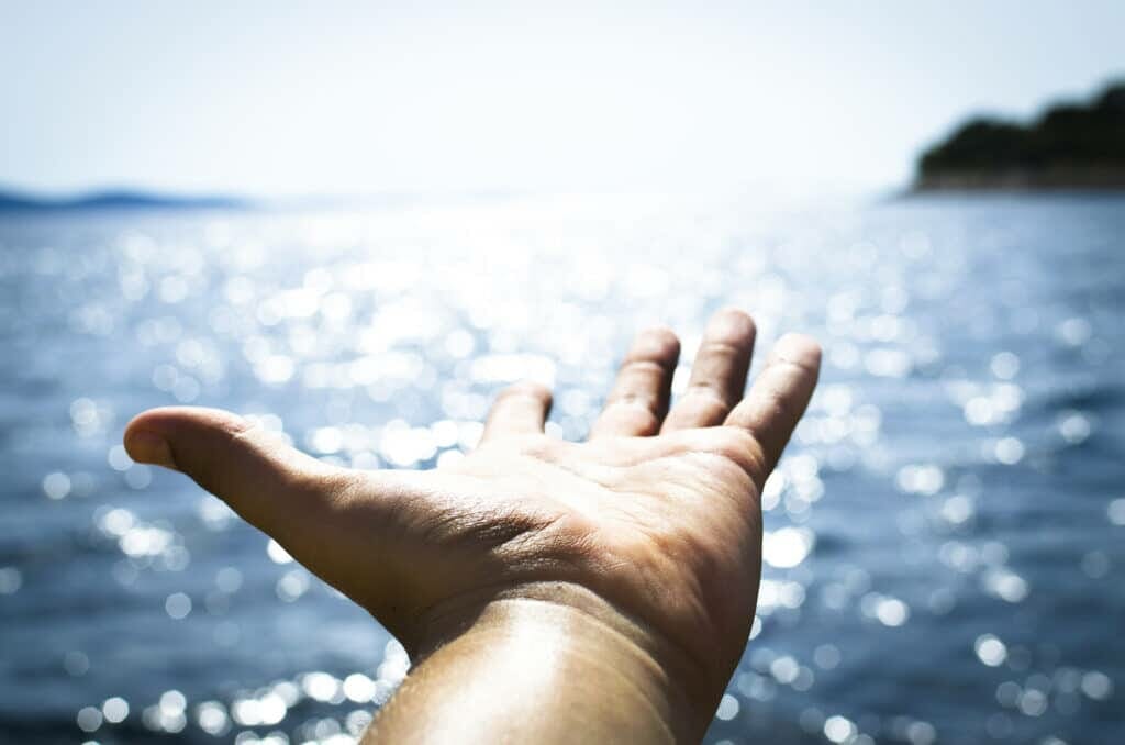 person hand reaching body of water stockpack pexels scaled