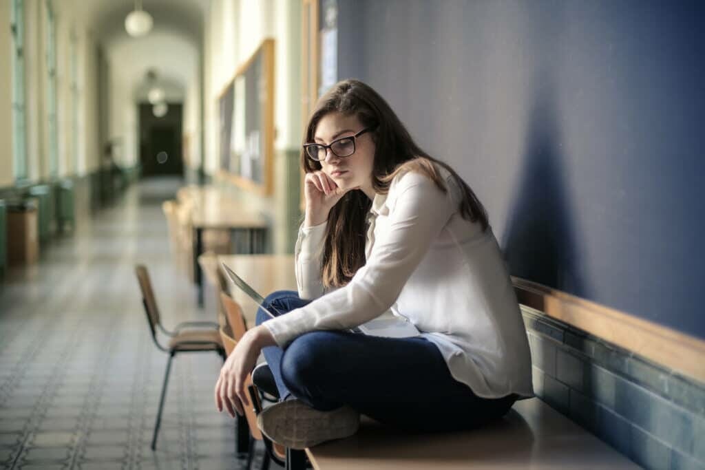 woman in white long sleeve shirt and blue denim jeans sitting on table stockpack pexels scaled