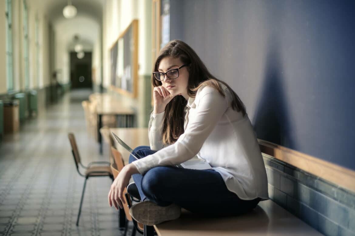 woman in white long sleeve shirt and blue denim jeans sitting on table stockpack pexels scaled