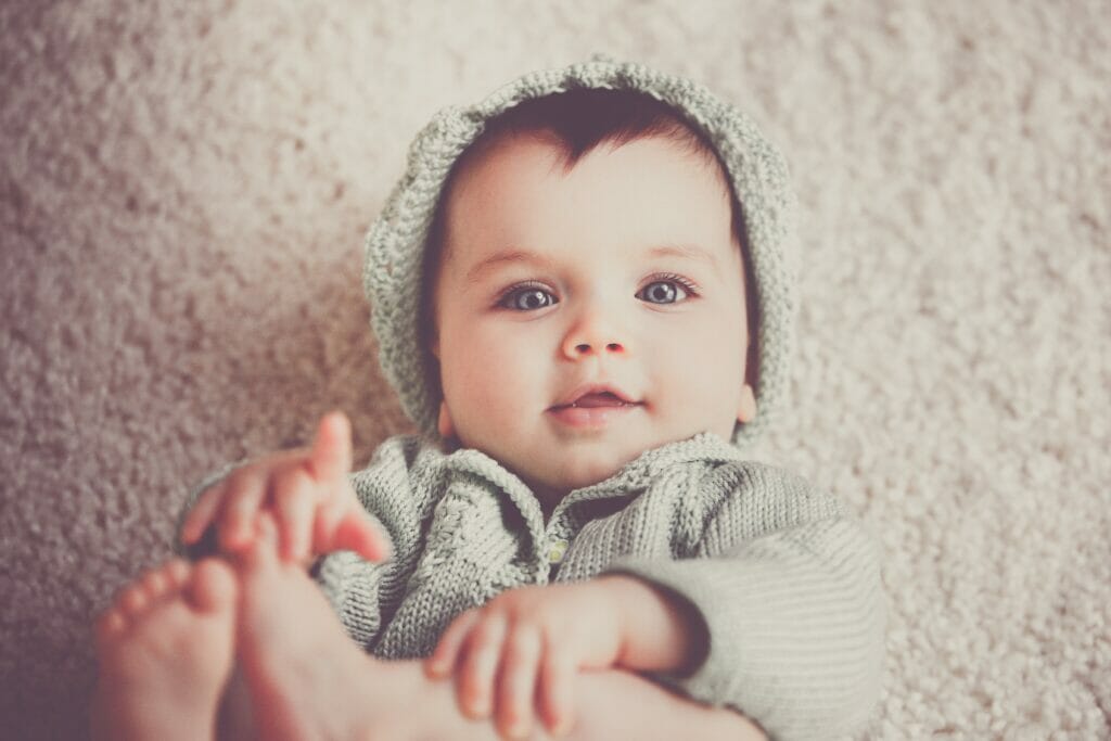 baby on gray knit hooded clothes lying on carpet stockpack pexels scaled
